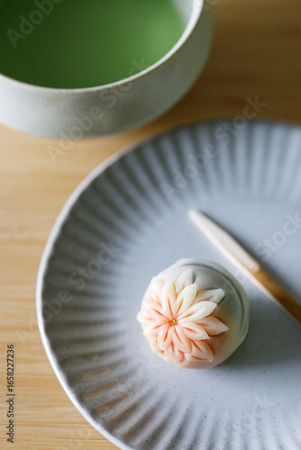 Cup of fresh matcha tea, green tea and Nerikiri, Japanese confectionery, on wooden table.