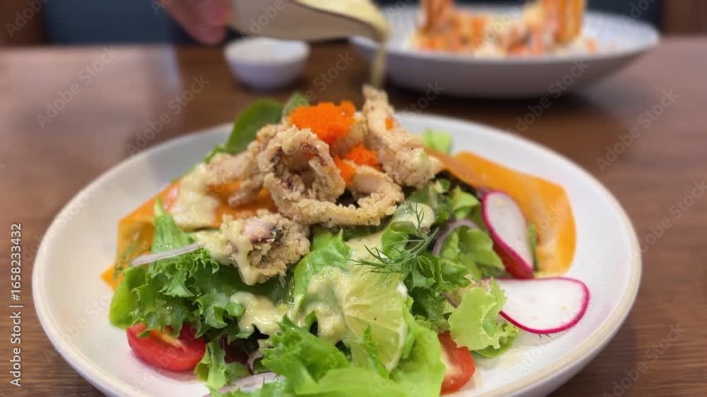 Salad with fried seafood and roe as creamy dressing is poured over fresh vegetables.
Salad with fried seafood and roe as creamy dressing is poured over fresh vegetables.