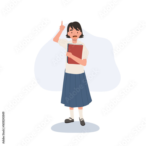 young thai primary schoolgirl in uniform holds a book and raises finger to share idea symbolizing learning confidence and education