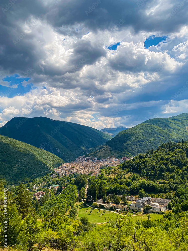 Obraz premium Scenic Scanno village nestled within Abruzzo mountains, revealing verdant landscape beneath brooding clouded sky