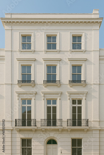 Elegant Neoclassical White Stone Facade of a Historic Residential Building, Showcasing Symmetrical Windows and Ornate Balconies in a Classic Urban Setting.