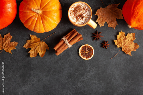Fototapeta Naklejka Na Ścianę i Meble -  Flat lay with pumpkins, pumpkin spice coffee in yellow mug, cinnamon sticks, dried citrus, star anise, and autumn maple leaves on dark stone background.