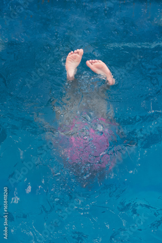 summer swimming in the pool. silhouette of a girl underwater, only heels are on the surface of the water