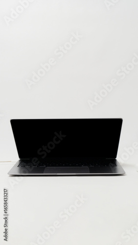 Minimalist laptop with half-open screen on white desk