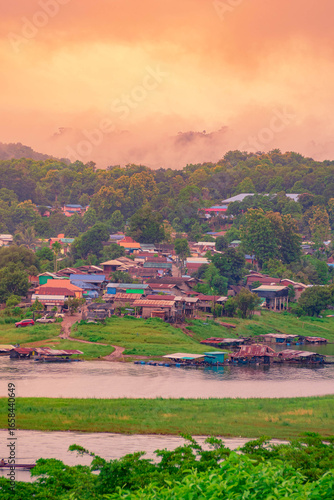 The Mon village in Kanchanaburi with morning mist on the green mountains and clear river.
