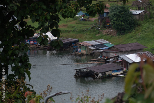 The Mon village in Kanchanaburi with morning mist on the green mountains and clear river.