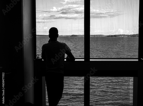 Person admiring the sea horizon from the windows of the cruise ship