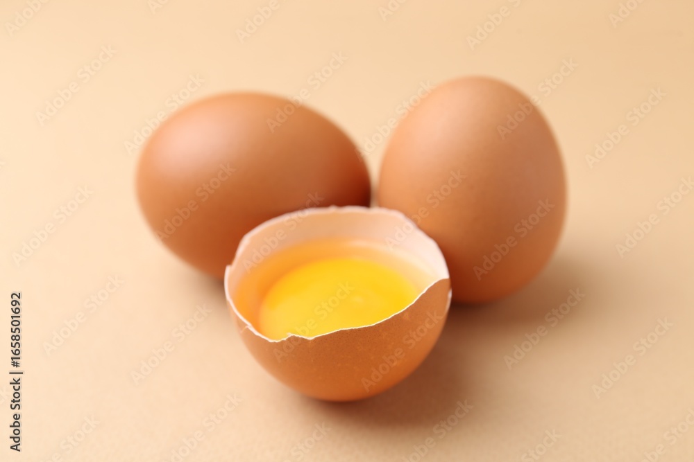 Whole and broken chicken eggs on beige background, closeup Whole and broken chicken eggs on beige background, closeup