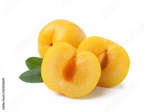 Whole and cut yellow cherry plums with leaves isolated on white
