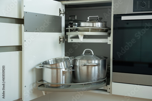 spacious kitchen cabinet showcasing neatly arranged stainless steel cookware including pots and lids on a rotating shelf for optimal storage and accessibility