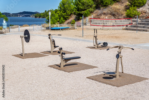 Fototapeta Naklejka Na Ścianę i Meble -  Public sports ground with volleyball court and modern exercise equipment for an outdoor workout by the sea at a vacation resort.Concept of a healthy and active lifestyle