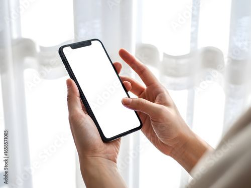 Hand holding smartphone with blank screen isolated in natural light background for app mockup and design presentation.