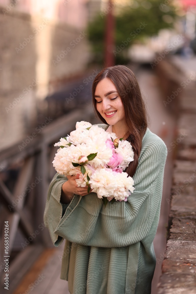 Fototapeta premium Charming woman with bouquet of beautiful peonies on city street