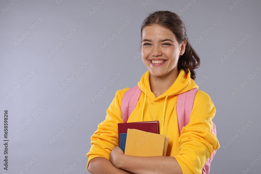 Obraz premium Student with notebooks happy about her good exam result on gray background