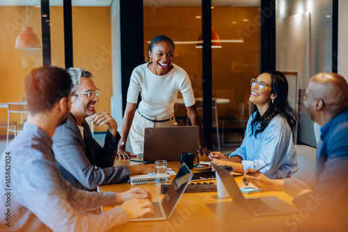 Diverse team engaged in discussion around a desk in a corporate office