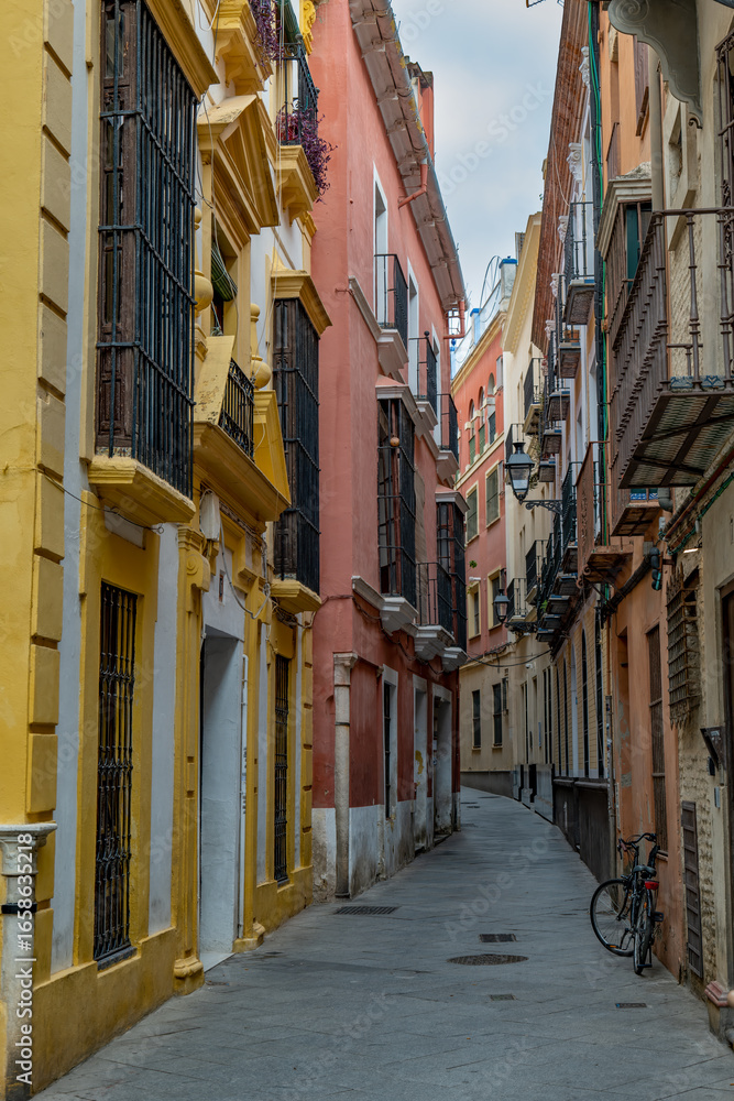 Fototapeta premium View of a Narrow Street in Barrio de Santa Cruz Neighborhood in Seville With Colorful Houses