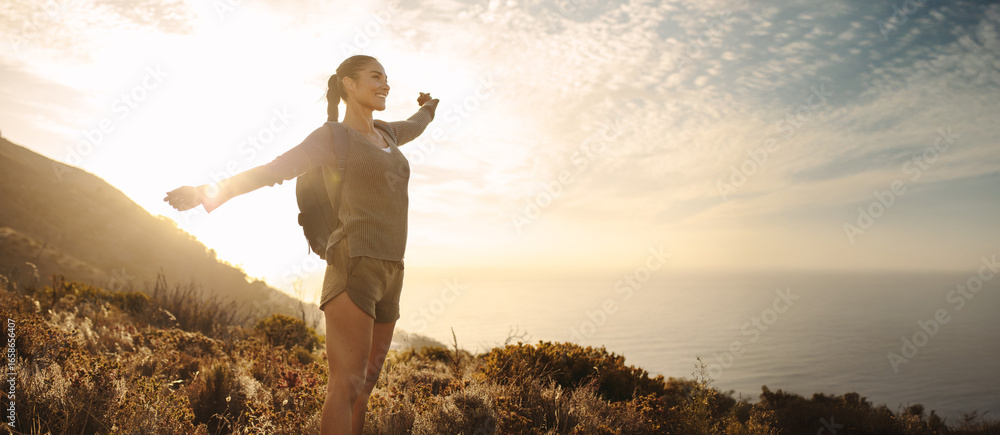 Obraz premium Woman embracing freedom while hiking near the ocean