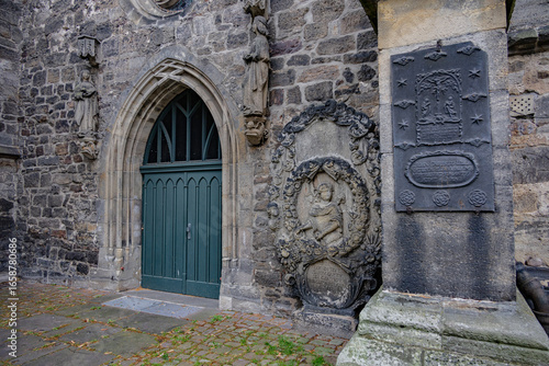 Wallpaper Mural Historic stone church entrance with Gothic door, religious sculptures, and old memorial plaques in Hann Münden Germany Torontodigital.ca