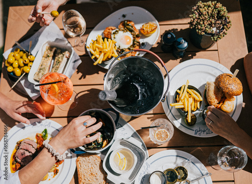 A table with a variety of food and drinks, including a bowl of fries, a sandwich