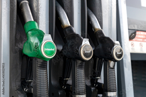 Fuel pump nozzles at a gas station showing unleaded and diesel options 