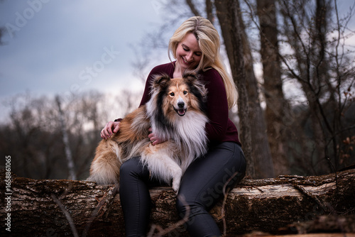 Woman smiling at Sheltie, dog looking at camera, affectionate