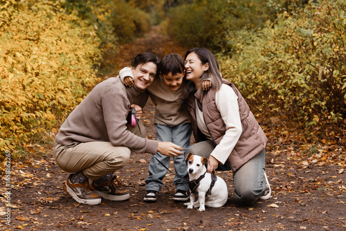 Wallpaper Mural Front view of young parents and son on a park with small dog, autumn forest background. Concept of family, active lifestyle, pet care, family health, mortgage and family security. Torontodigital.ca