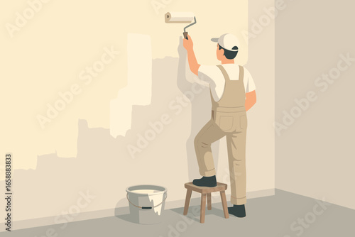 A worker painting an interior wall with a roller, standing on a small stool. The room is partially painted, with a bucket of paint nearby. The setting