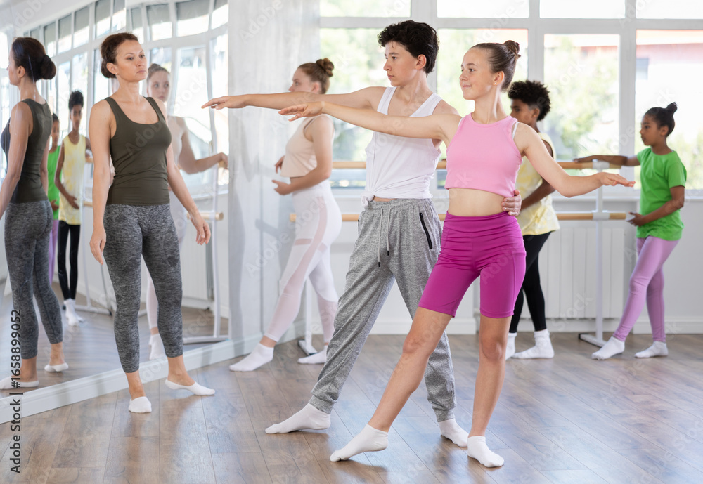 Naklejka premium Teen boy and teen girl perform paired ballet dance in studio