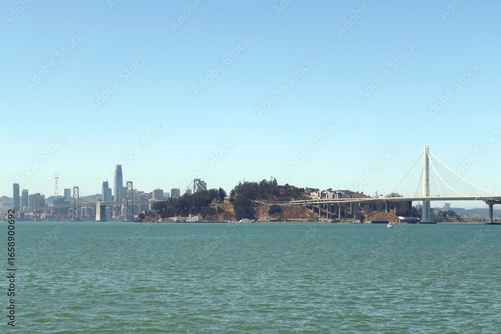 Obraz premium Panoramic view from Oakland across the San Francisco Bay, featuring Yerba Buena Island, the Bay Bridge, and the iconic San Francisco skyline on a clear day.