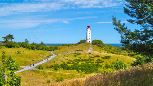 Dornbusch Lighthouse on Hiddensee – white lighthouse with red cap nestled in green landscape along the Baltic Sea coast.