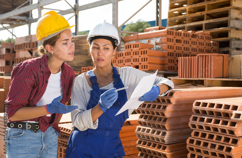 Fototapeta Couple of female wokers checking order list at hardware store warehouse
