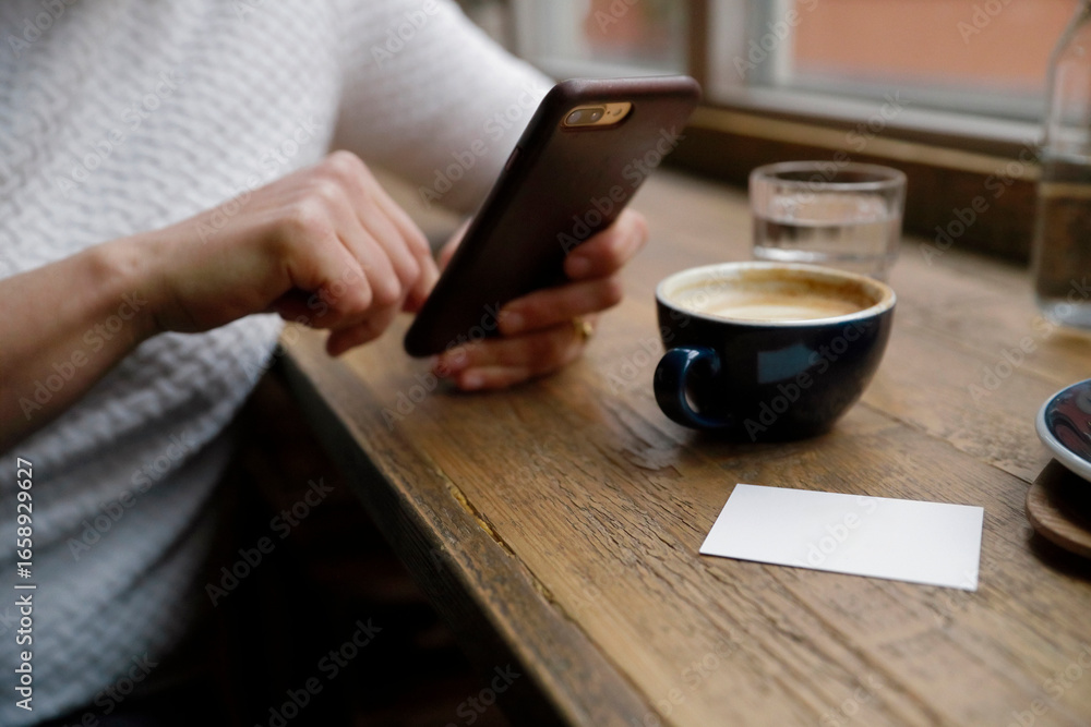 Hand holding smartphone with business card and coffee creating professional networking scene Hand holding smartphone with business card and coffee creating professional networking scene