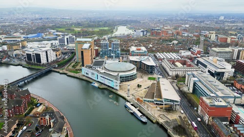 Aerial drone view of cars driving over the buildings surrounding River Lagan