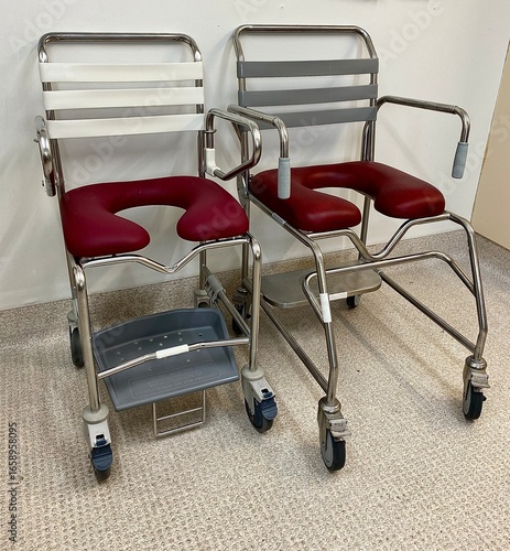 Two commode and shower chairs with maroon U-shaped seats and metal frames