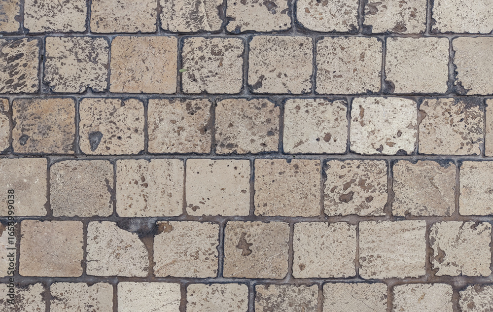 Obraz premium Close-up of stone pavement with square tiles in earthy tones. The rough surface and natural texture highlight durability. Urban design and the timeless beauty of traditional walkway construction.