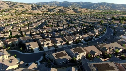 Aerial View of Suburban Neighborhood with Solar Panels and Rolling Hills