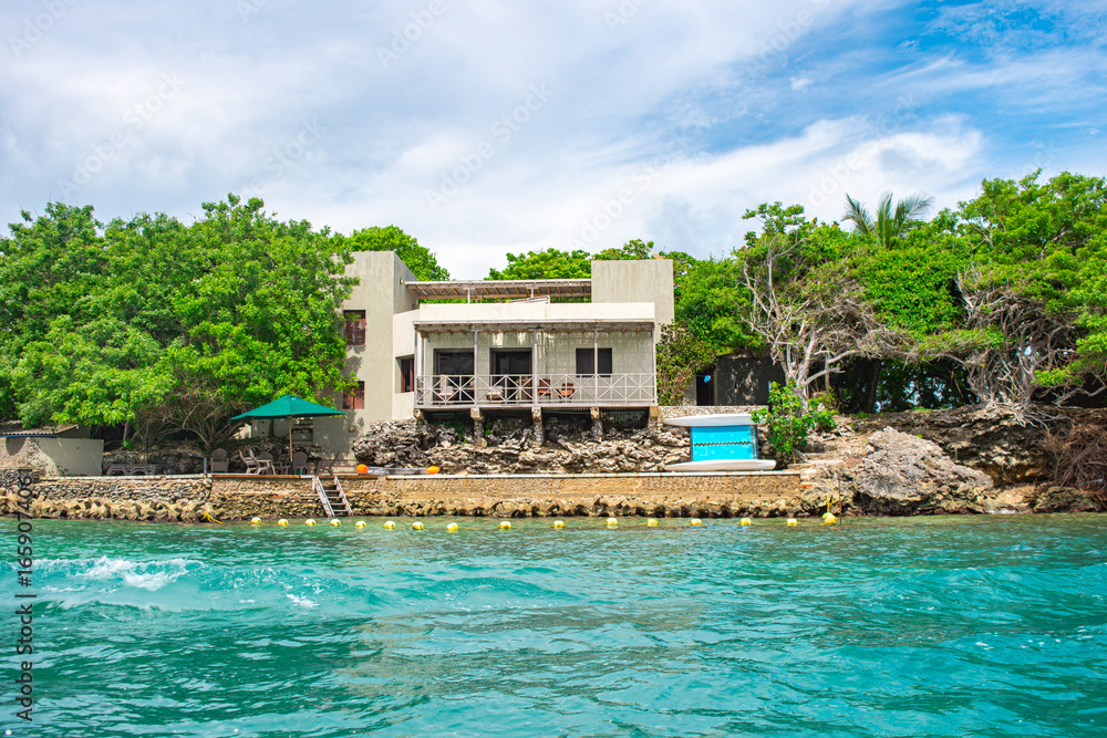 Obraz premium Breathtaking view of a modern house on Rosario Island, surrounded by lush greenery and turquoise waters in Cartagena, Colombia.