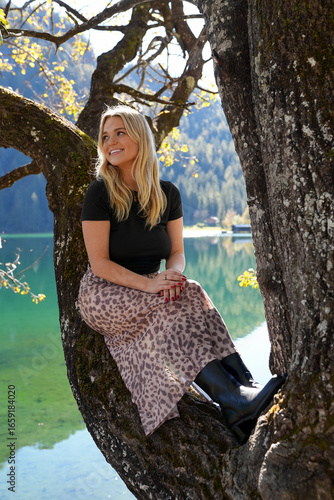 Woman Sitting in a Tree with a Beautiful Lake