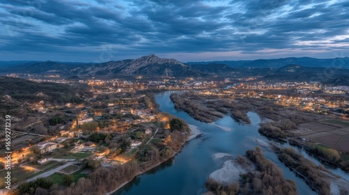 Aerial view of a serene river winding through a picturesque valley at dusk, with glowing lights