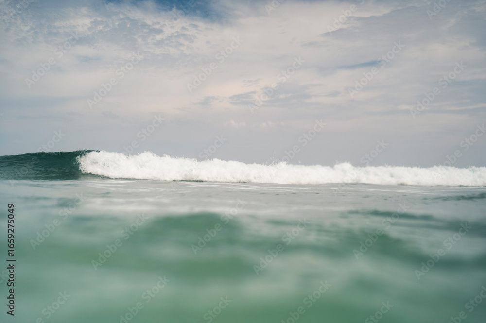 Fototapeta premium Ocean wave cresting under cloudy sky