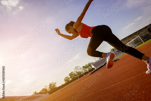 Silhouette of fit young woman running sprinting at the racetrack. Fit runner fitness runner during outdoor workout at racetrack 