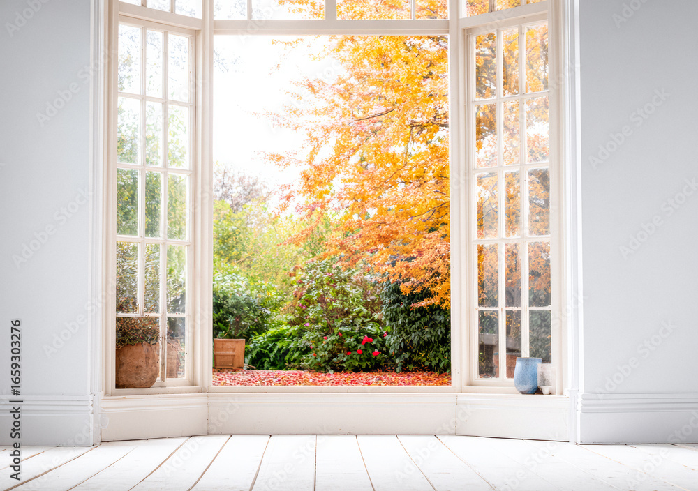 Obraz premium Bright autumn view through open windows showcasing vibrant foliage and tranquil garden in a cozy interior
