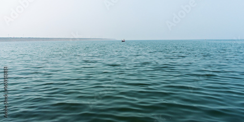 Serene Ocean View With Calm Waves and Distant Boat Under Clear Sky