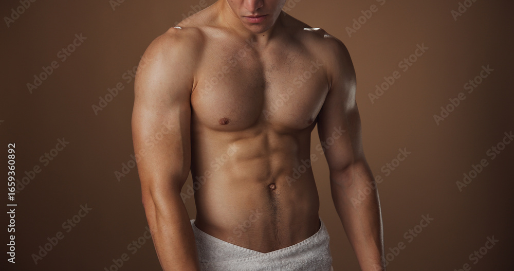 Fototapeta premium Body, abs and muscle of man in studio with space, biceps or pectoral with grooming on brown background. Skin, hygiene and strong male person with six pack, stomach and self care for cleanliness