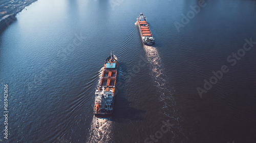 Two cargo vessels moving along a wide river in morning mist — perspective shot about transport and logistics scale.