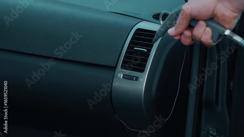 A skilled hand uses a professional tool to clean car air vents for better airflow, efficiency, and hygiene