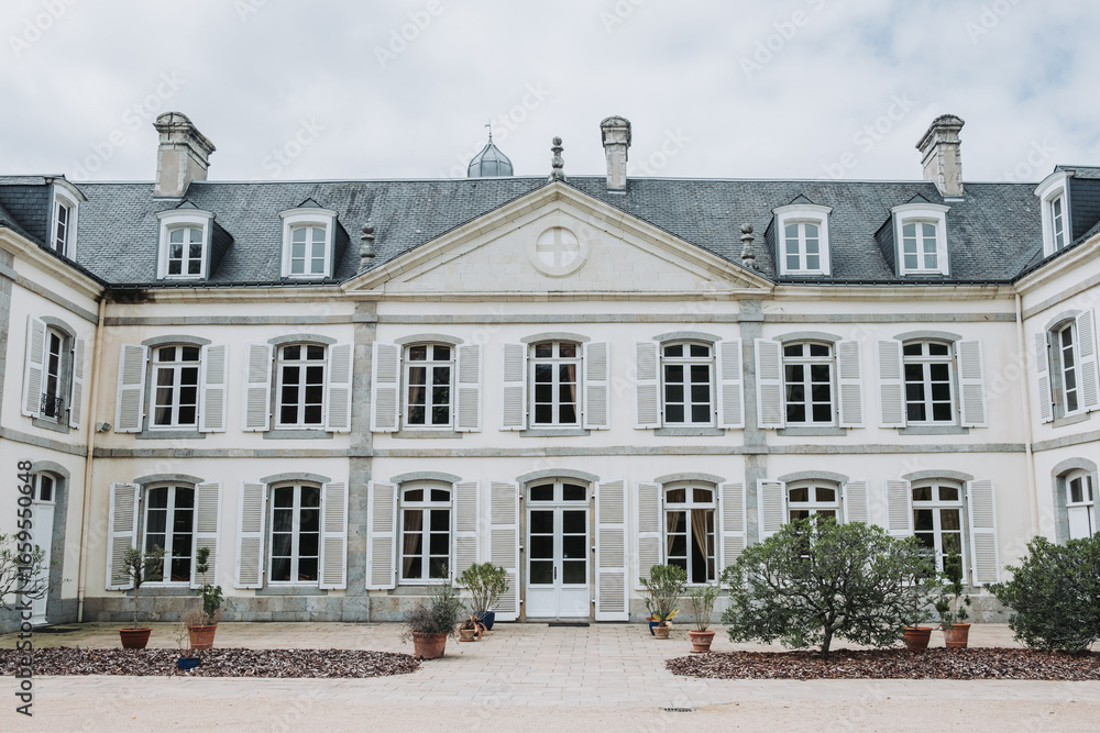 Obraz premium Exterior side view of French château wedding venue with terrace and shutters