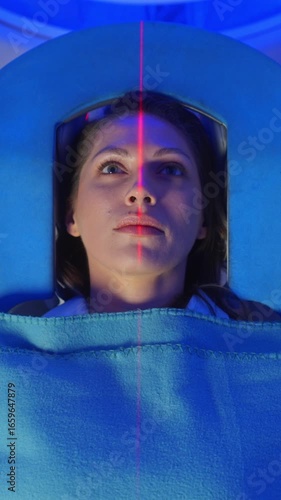 Medical Laboratory or Healthcare Facility with High-Tech Equipment: Portrait Shot of Female Patient Lying on a CT or MRI Scan, Bed is Moving Inside the Machine While it Scans her Brain. Top Down View