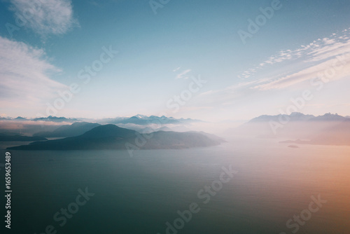 Serene aerial view over misty mountains and calm sea