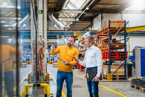 Businessman and manager discussing in production hall at factory